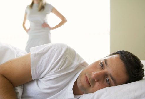 man lying in bed, woman standing in background