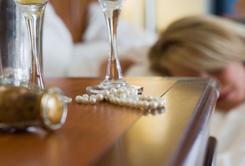 Sleeping woman with empty wine glass near bed