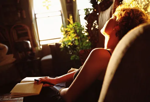 Woman writing in diary in sunlight at home