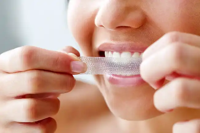 woman using teeth whitening strip