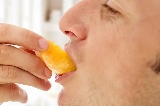 man eating piece of orange