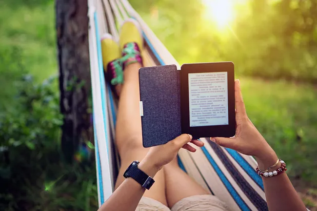 photo of woman using e-reader in hammock