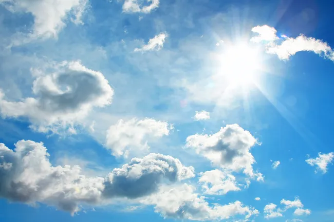 photo of sun and clouds against blue sky