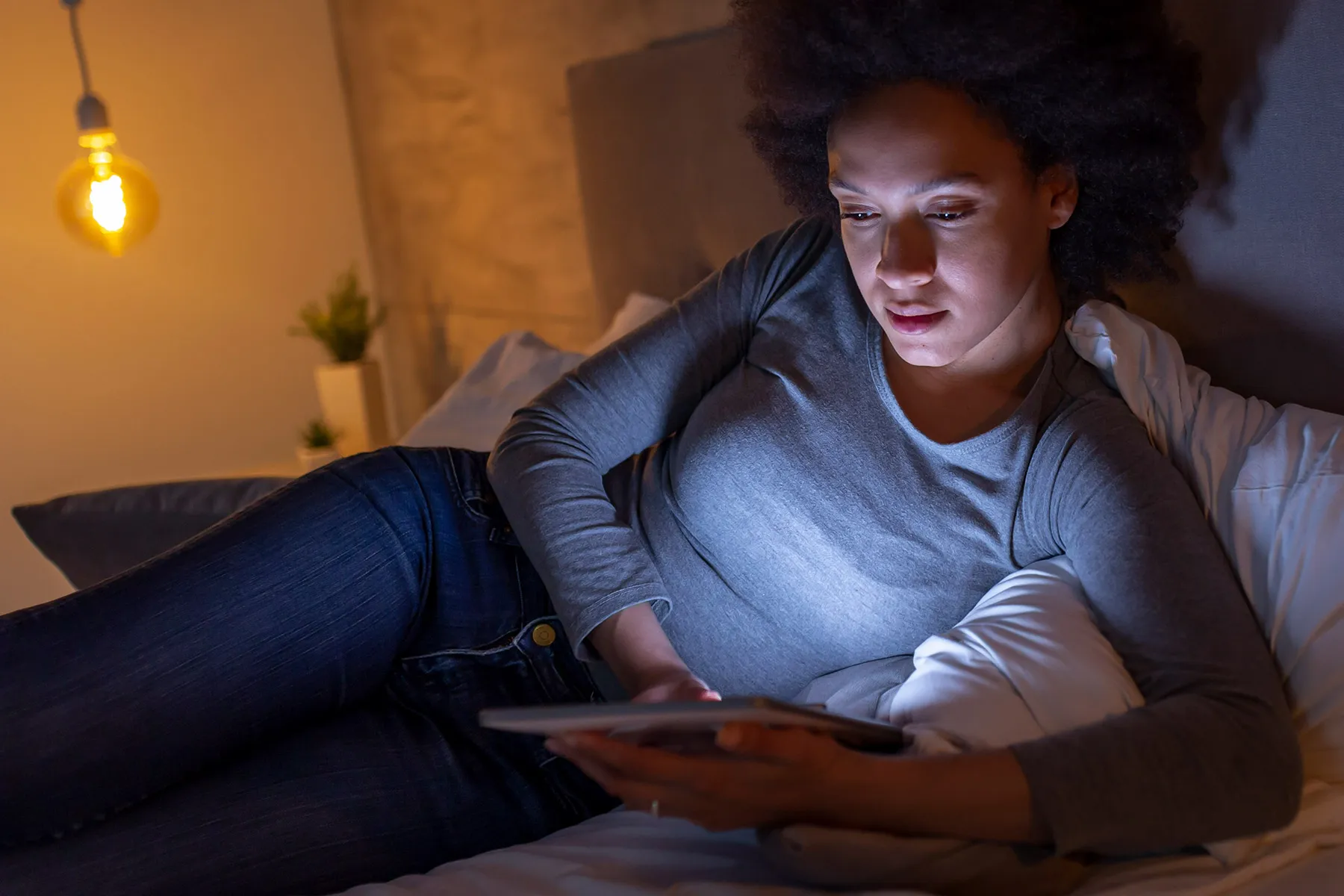 photo of woman using computer tablet on bed