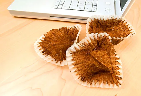 Empty cupcake wrappers beside laptop