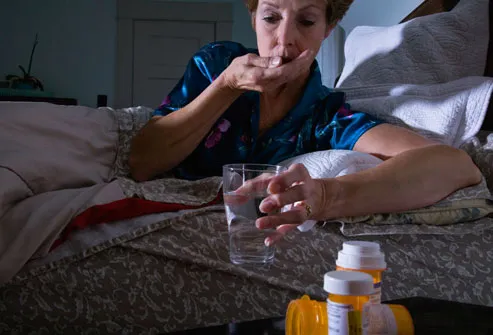 Woman In Bed Taking Pills