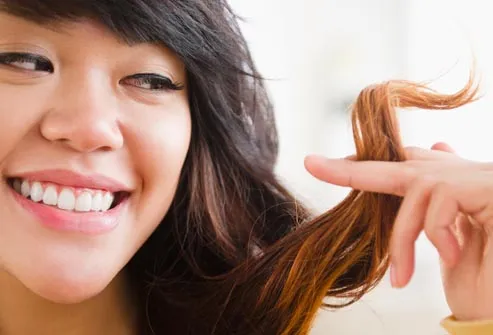 smiling woman looking at her hair