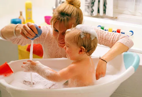 Mom bathing baby in small plastic tub to conserve