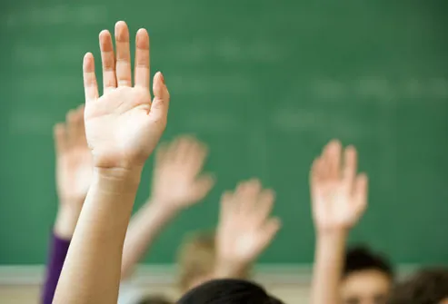 Children raising hands in class