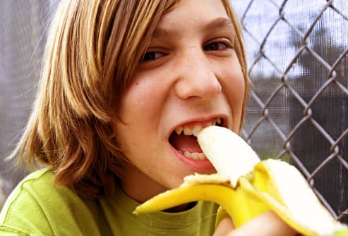 Teen boy eating banana