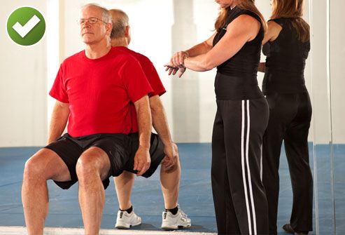 Man Doing Wall Sit With Trainer Timing