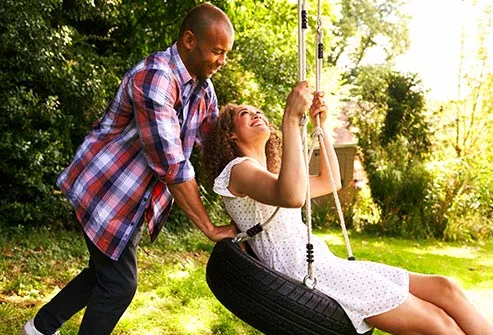 man pushing woman on swing