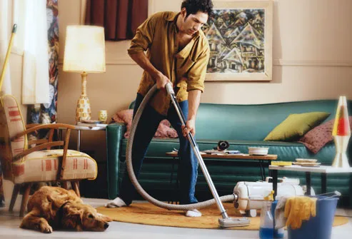 man vacuuming with labrador revtriever watching