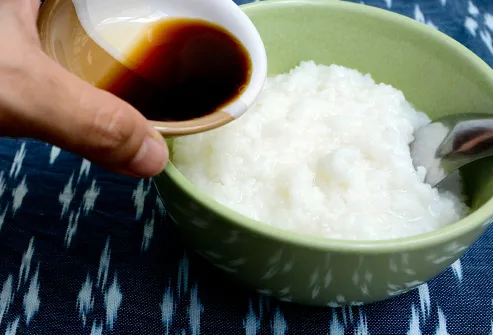 pouring soy sauce into bowl of rice