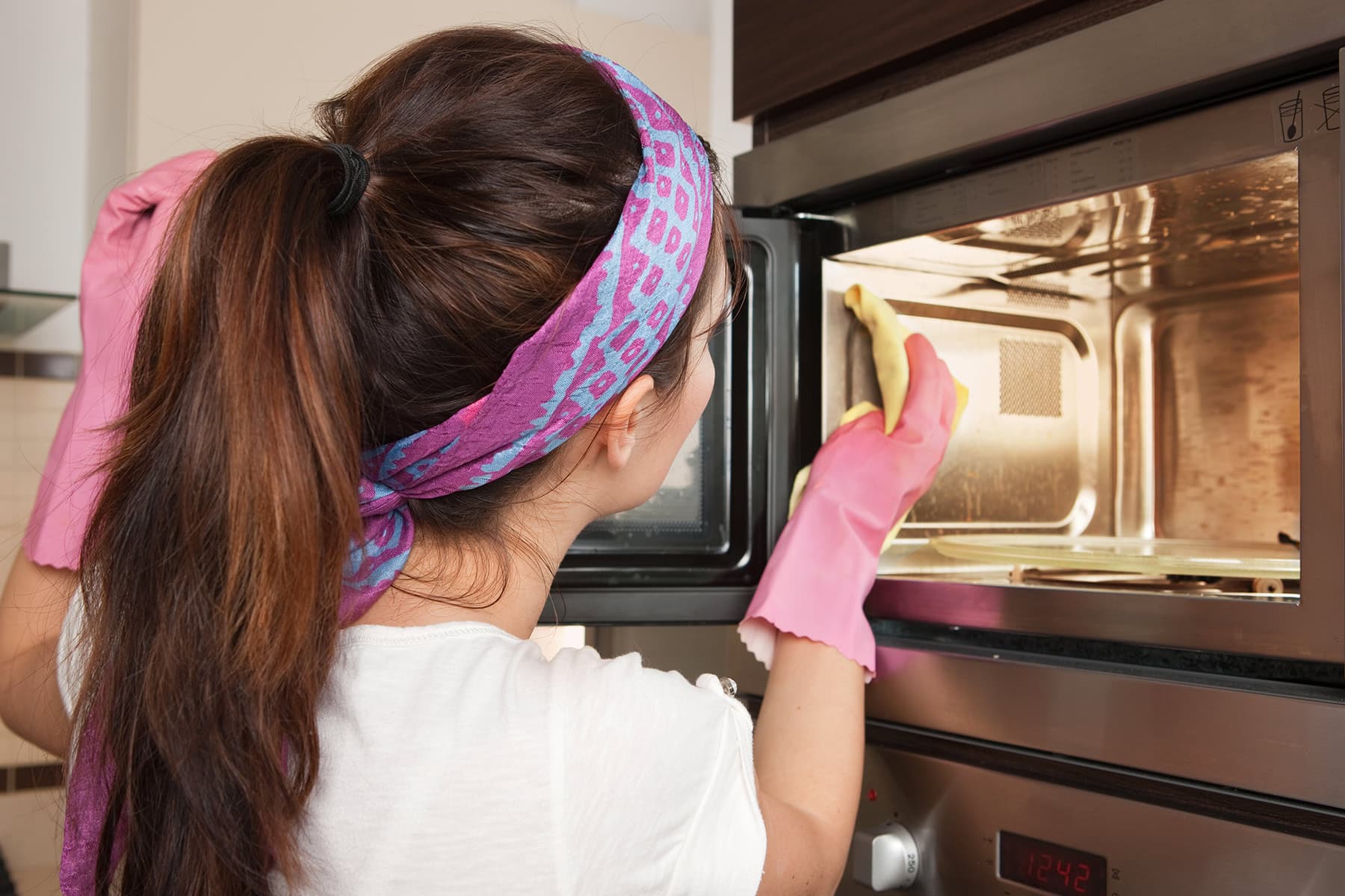 photo of woman cleaning microwave oven