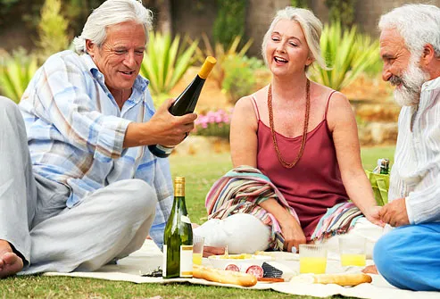 Three mature friends having  picnic with wine
