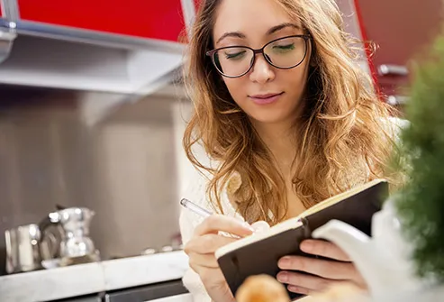 woman taking notes in kitchen