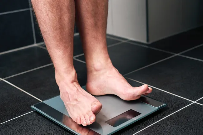 man’s feet on weight scale