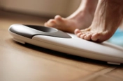 photo of woman stepping onto weight scale