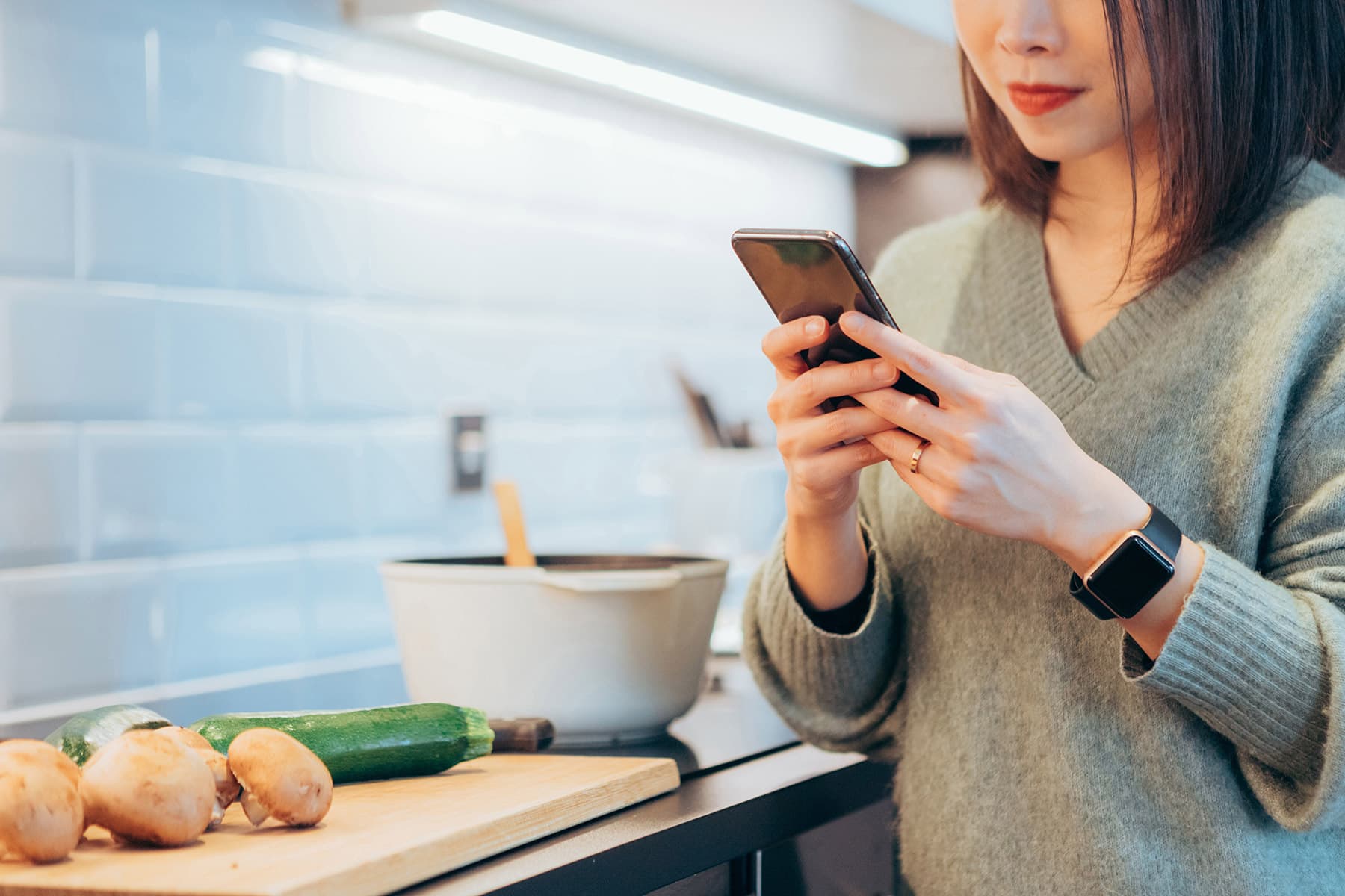 photo of young woman using smartphone in kitchen