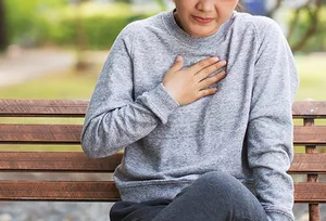 woman with heartburn on park bench