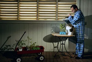 Man in pajamas watering plants late at night