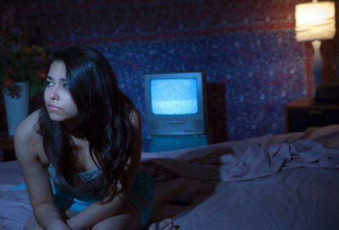 Hispanic woman kept awake by glowing television