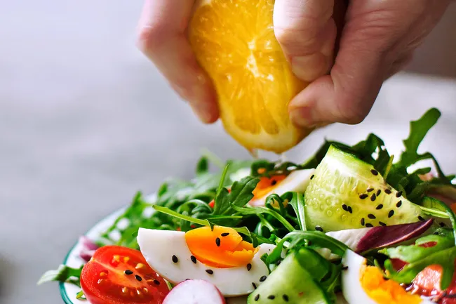squeezing orange on salad