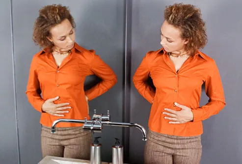 Pregnant woman looking at her belly in mirror