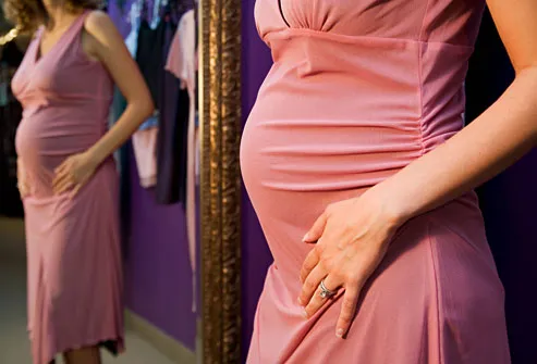 Pregnant woman trying on dress in store