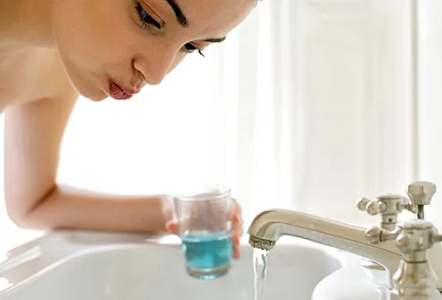 woman using mouthwash