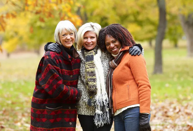 Three women standing in park, smiling