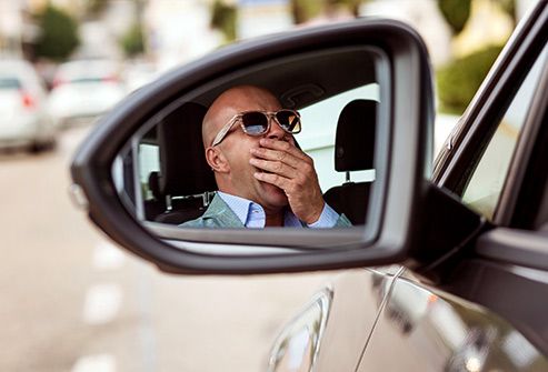 man yawning in car