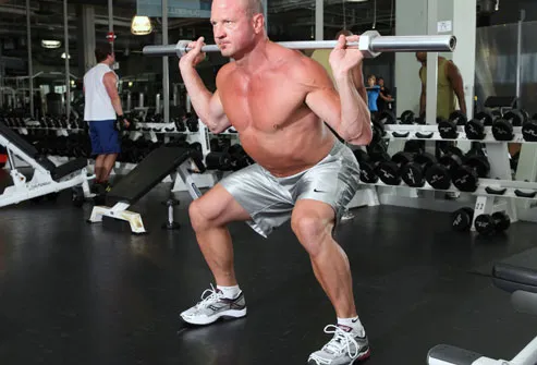 Trainer demonstrating squat with barbell