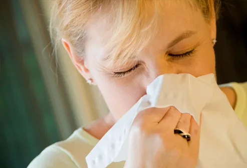 woman using tissue to blow nose