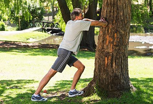 man stretching against tree