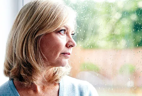 mature woman looking out glass door
