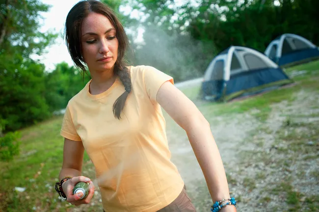 photo of woman spraying bug spray