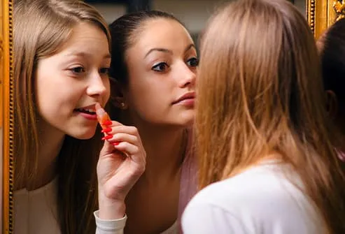 teens puting on lipgloss