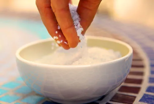 Hand pinching sea salts from bowl