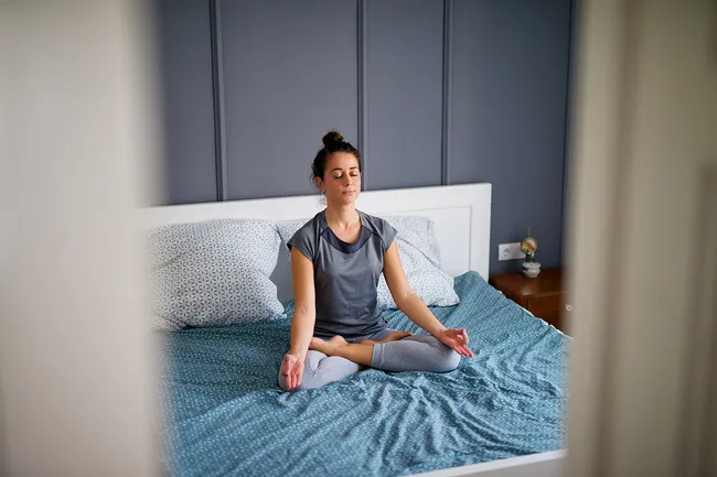 photo of woman meditating on bed
