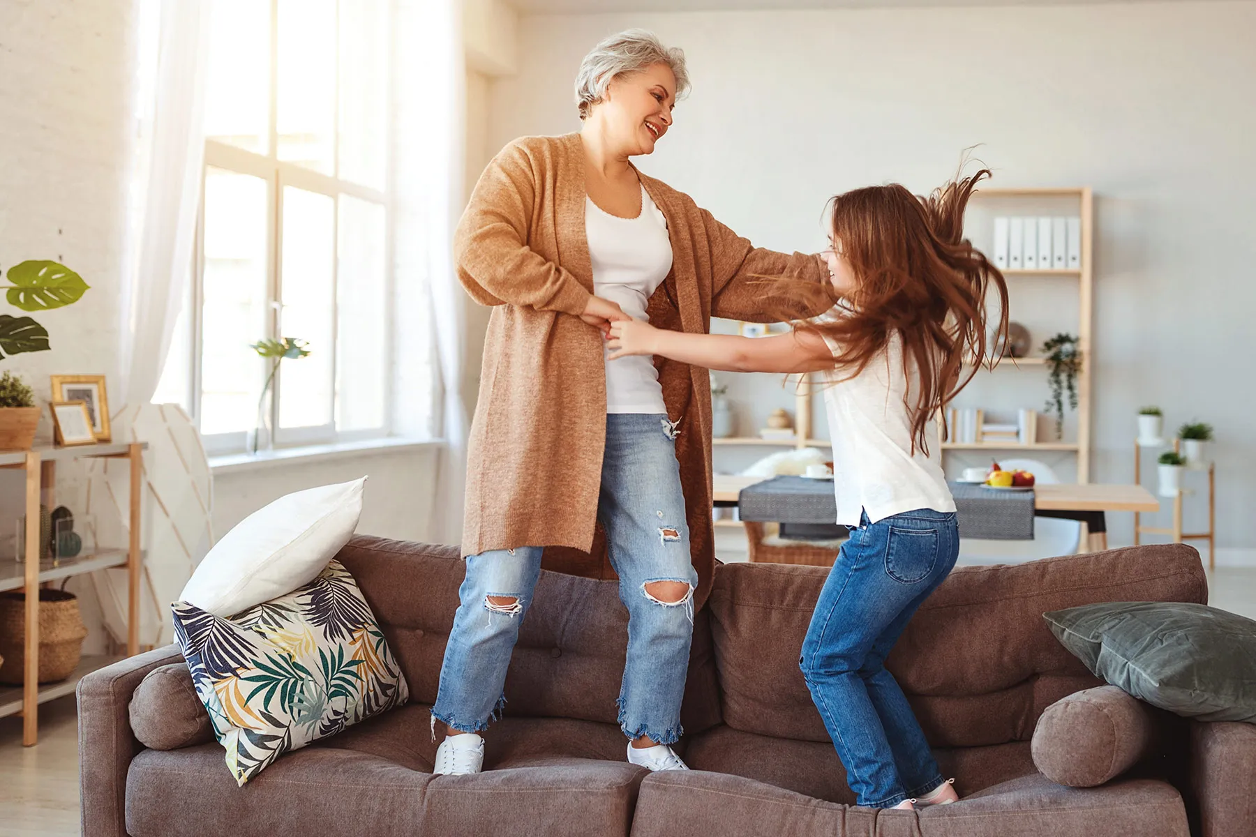 photo of mother and daughter jumping on sofa