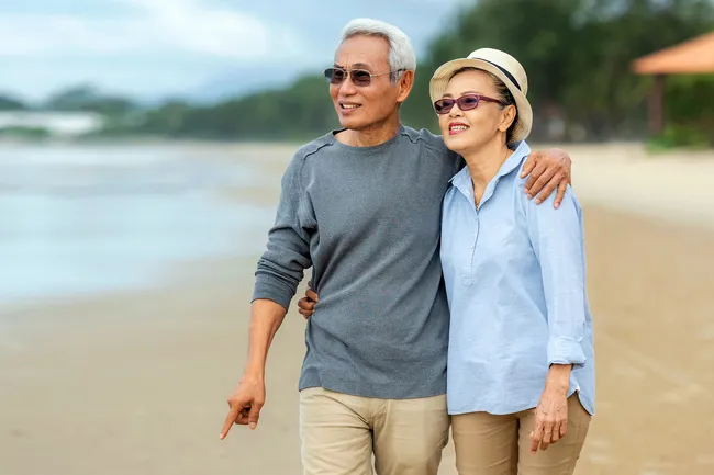 photo of mature couple walking on the beach