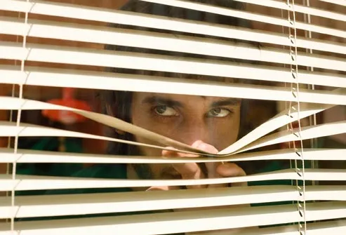 suspicious man peering through blinds