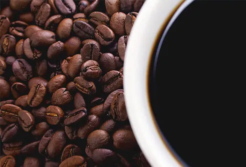 Close-up of coffee beans and cup, cup out of focus