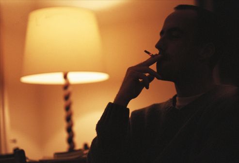 Man smoking by electric lamp, silhouette
