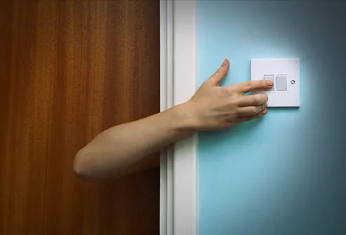 Person reaching round door to touch light switch