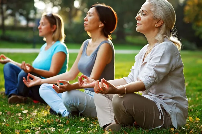 photo of mature women meditating in park