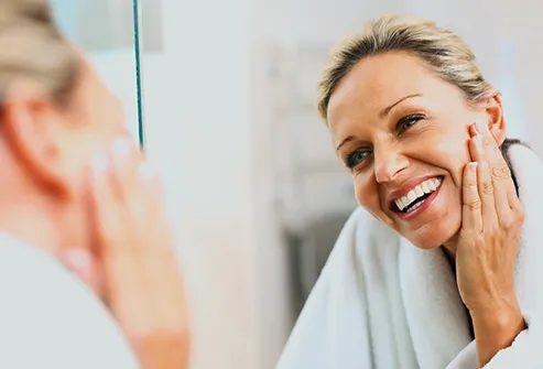 woman looking at face in mirror