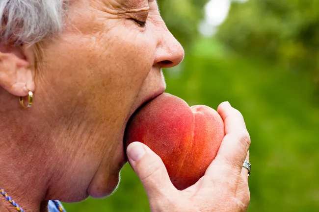 mature woman eating peach